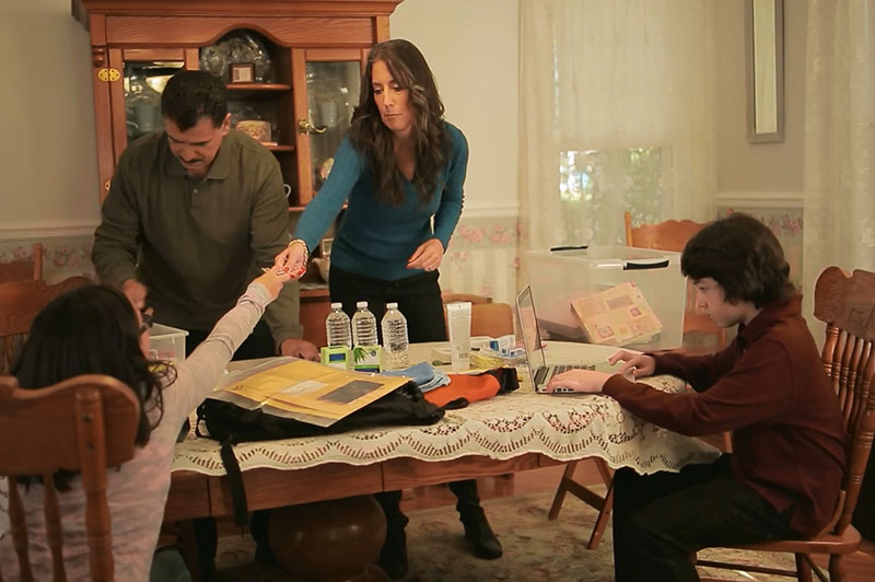 A family preparing for an emergency together at the dining room table of their home.
