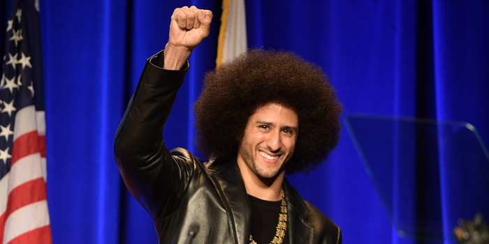 Photo of Colin Kaepernick with a smile and his fist raised high
