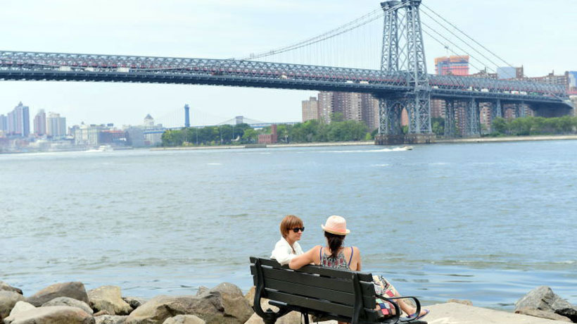 two women sitting on the bench in front of Williamsburg Bridge
                                           
