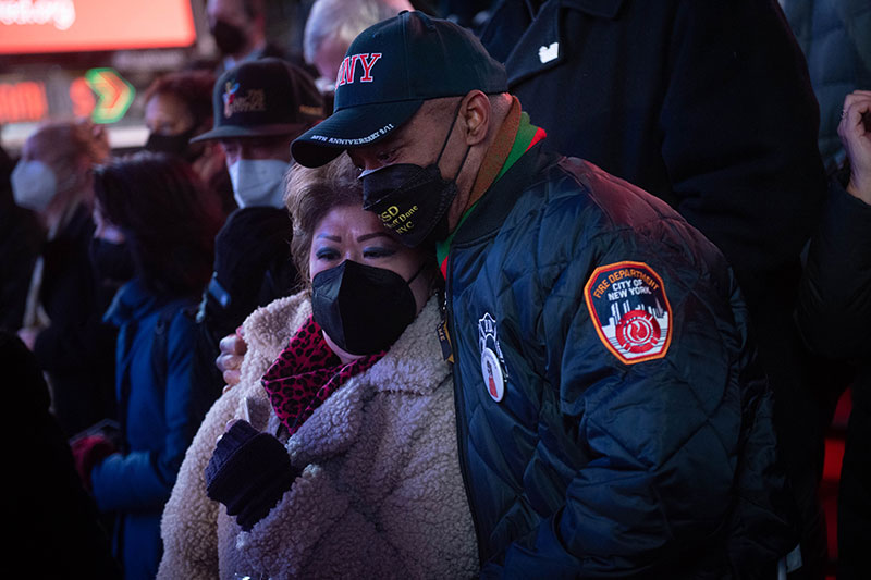 Man in FDNY jacket hugging a woman from the side