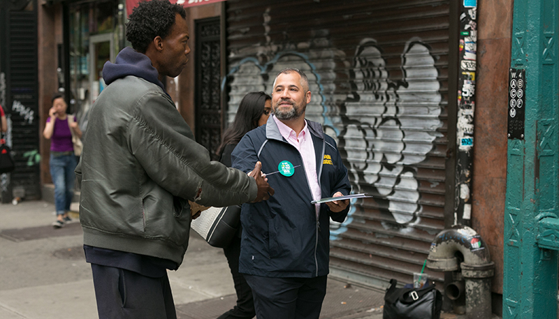 Commission staff member distributing literature to a passerby near the subway.