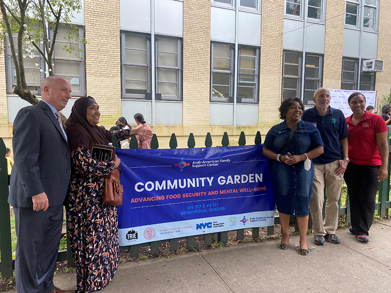 School officials & Community leaders stand in front of  Community Garden banner