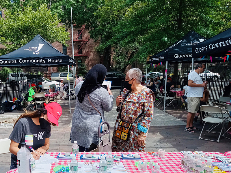 Outreach staff sharing information about the August Primary with Queens Resident