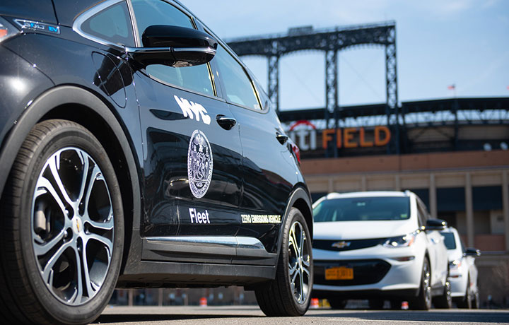 Black EV with Fleet logo, CitiField in the background on a sunny day.  
                                           