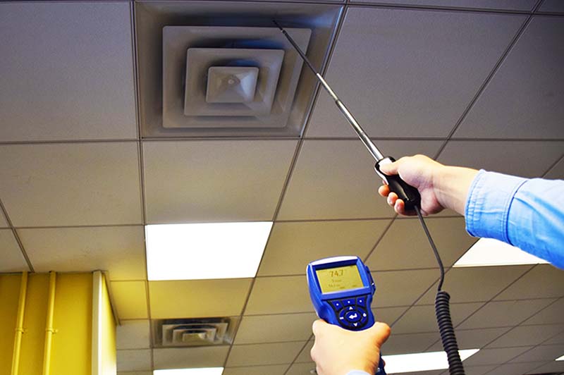 Staff member conducting an energy audit using a hand-held meter.