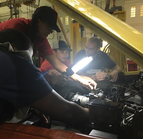 Automotive High School interns examine under the hood of a car