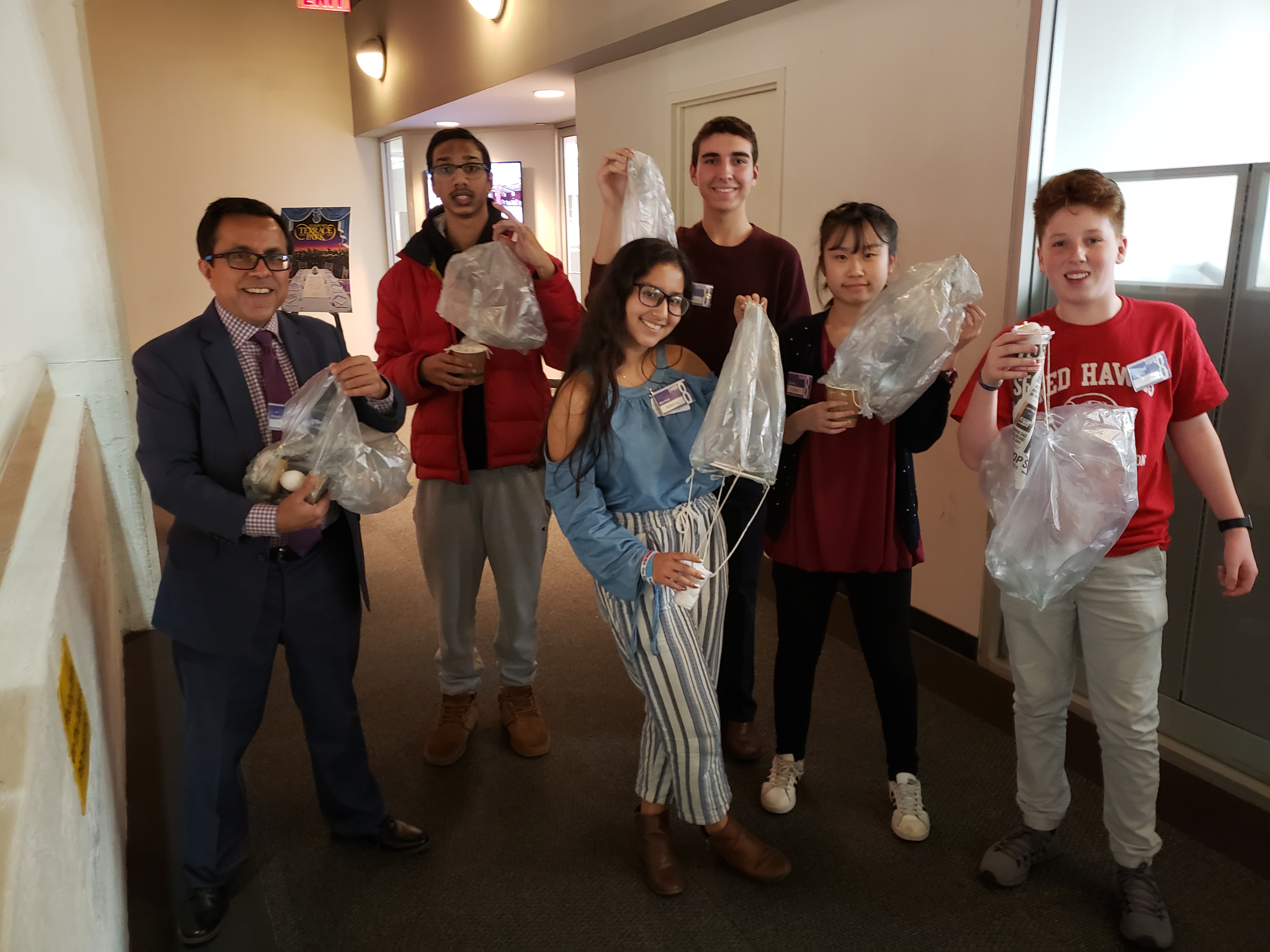 Ace students and their mentor hold up plastic bags in a group photo.