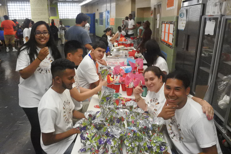 High school and college interns sit at a table, where they prepare goodie bags for District 9 teachers and staff.