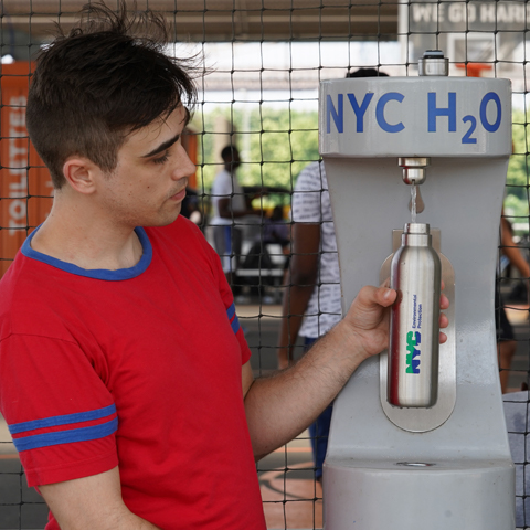 A gentleman is filling a water bottle in front of a water fountain in NYC