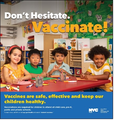 Young children, smiling, sitting at a table in a classroom. Poster text states: Don’t hesitate. Vaccinate! Vaccines are safe, effective and keep our children healthy.