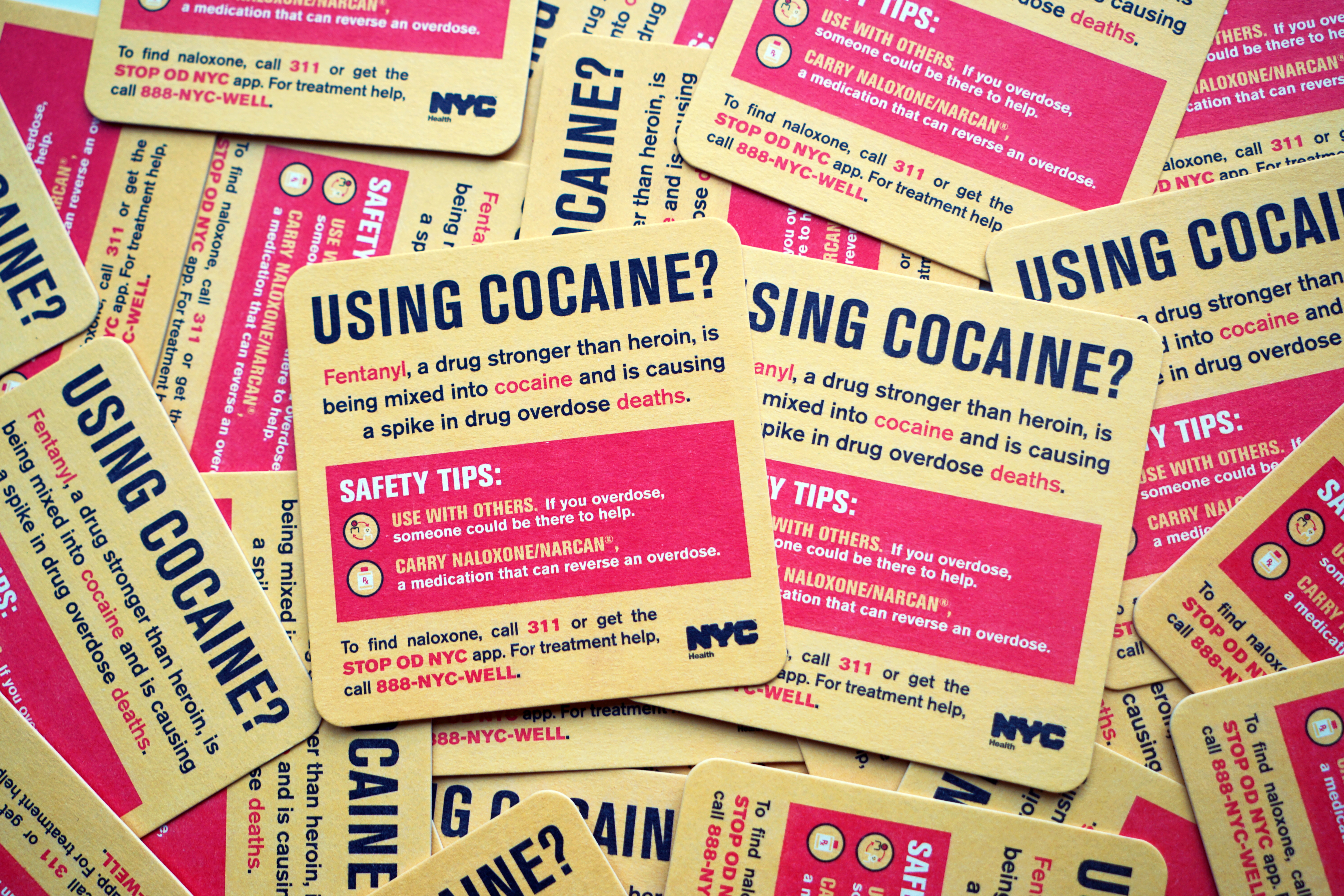 A pile of coasters titled Using Cocaine?. Each coaster provides information about fentanyl, including that it can be added to cocaine without the user knowing. It also provides safety tips for cocaine users.