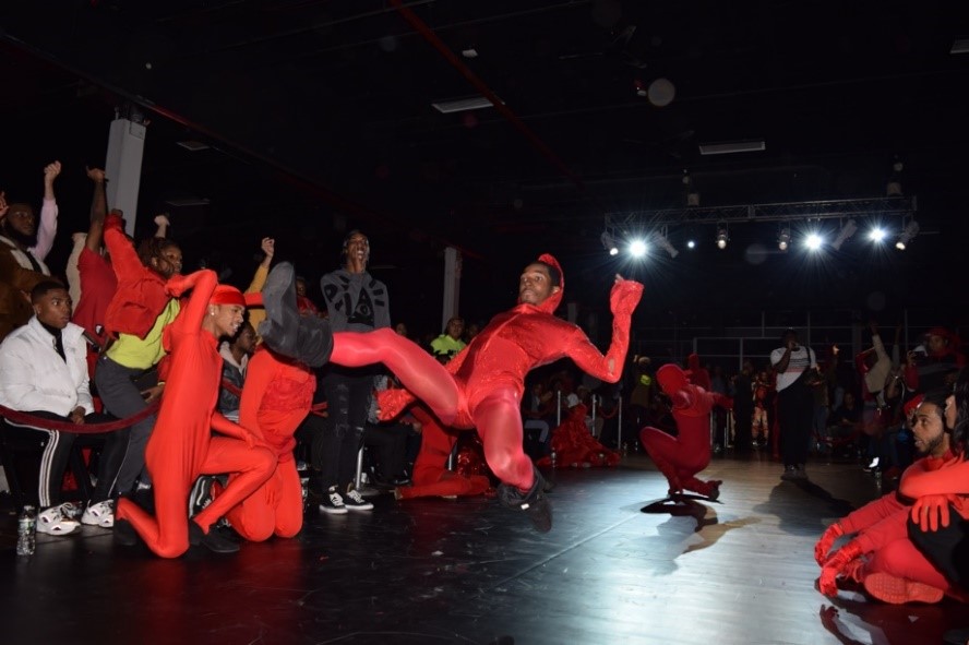 A man dressed in all red dancing on the RED Revolution runway.