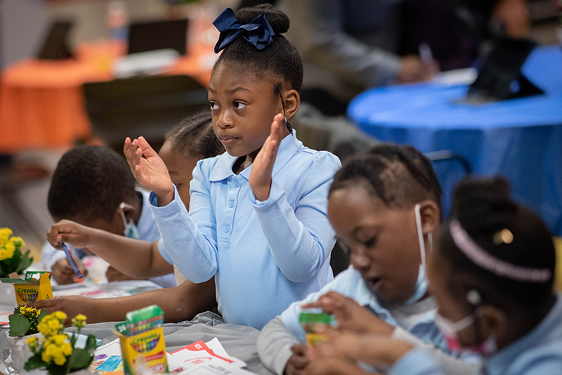An adorable student applauds at the Save for College Program event.