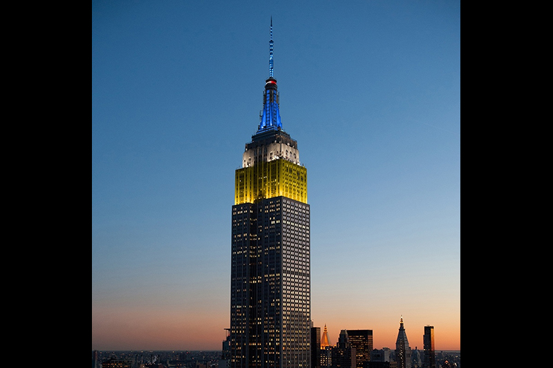Empire State Building illuminated in yellow, white and blue 