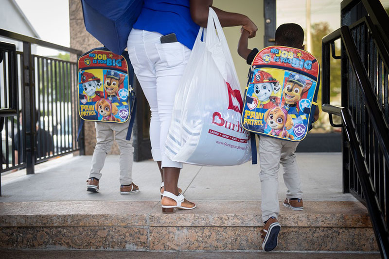 Parent taking two kids to school with Paw Patrol backpacks.