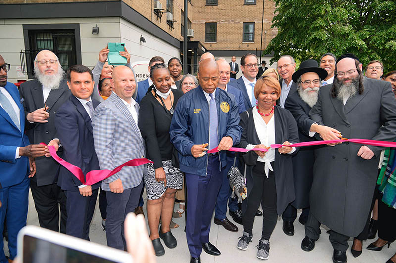 New York City Mayor Eric Adams and others cut red ribbon at a public housing development in Brooklyn