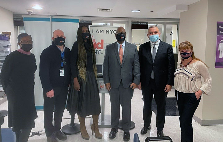 MOIA and DSS Commissioners pose with IDNYC staff members by IDNYC poster
                                           