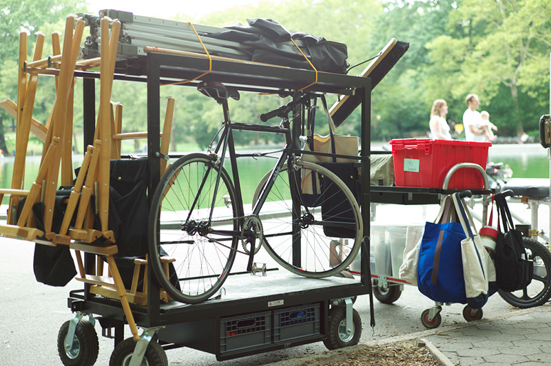 Photo of a bicycle, directors chairs, and other film equipment on a two equipment carts.
