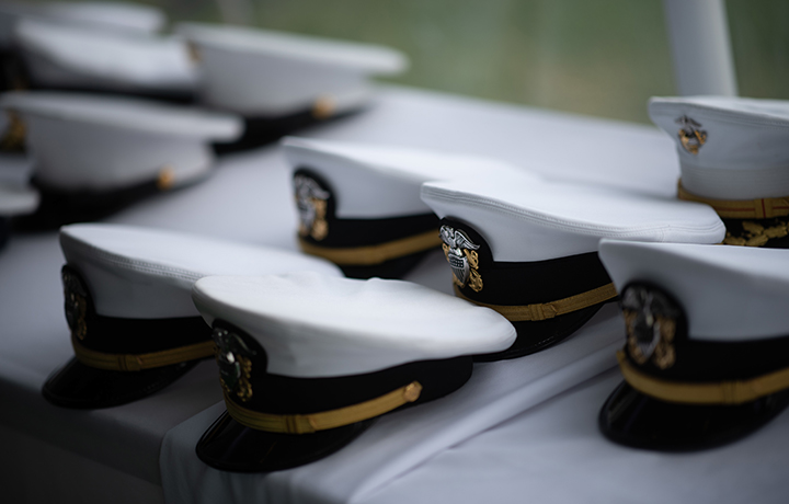 Several white U.S. Marine caps sit on a table with a white tablecloth