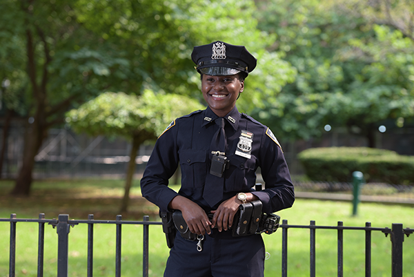 NYPD Officer smiling at park fence