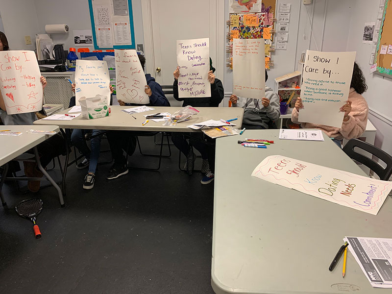 Students in a classroom showing up signs