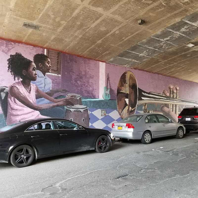 Cars parked in front of a mural.