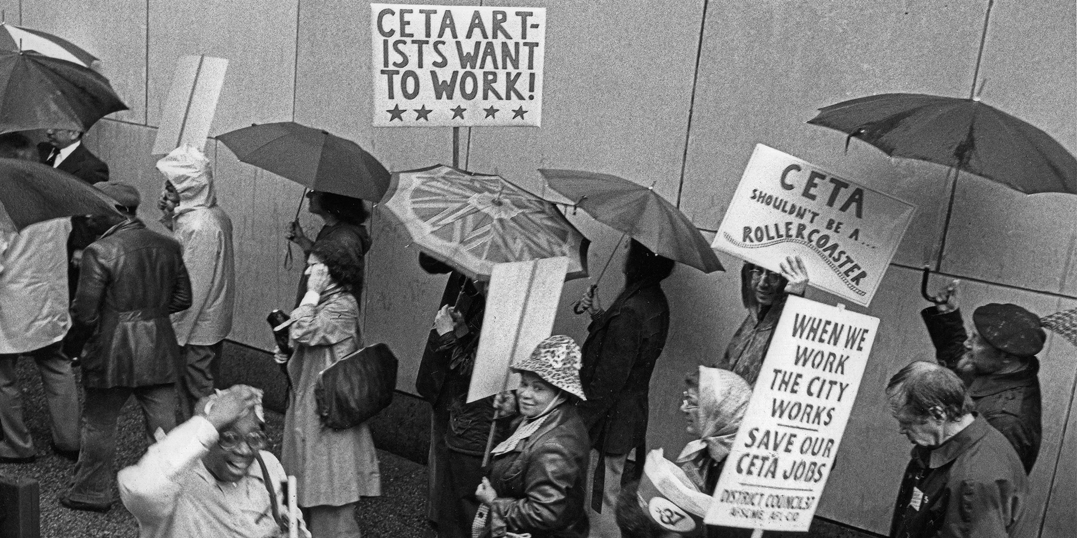 People marching holding umbrellas and signs during CETA protest to save artists jobs