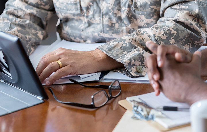 Photo of a veteran sitting at a table using a tablet
                                           