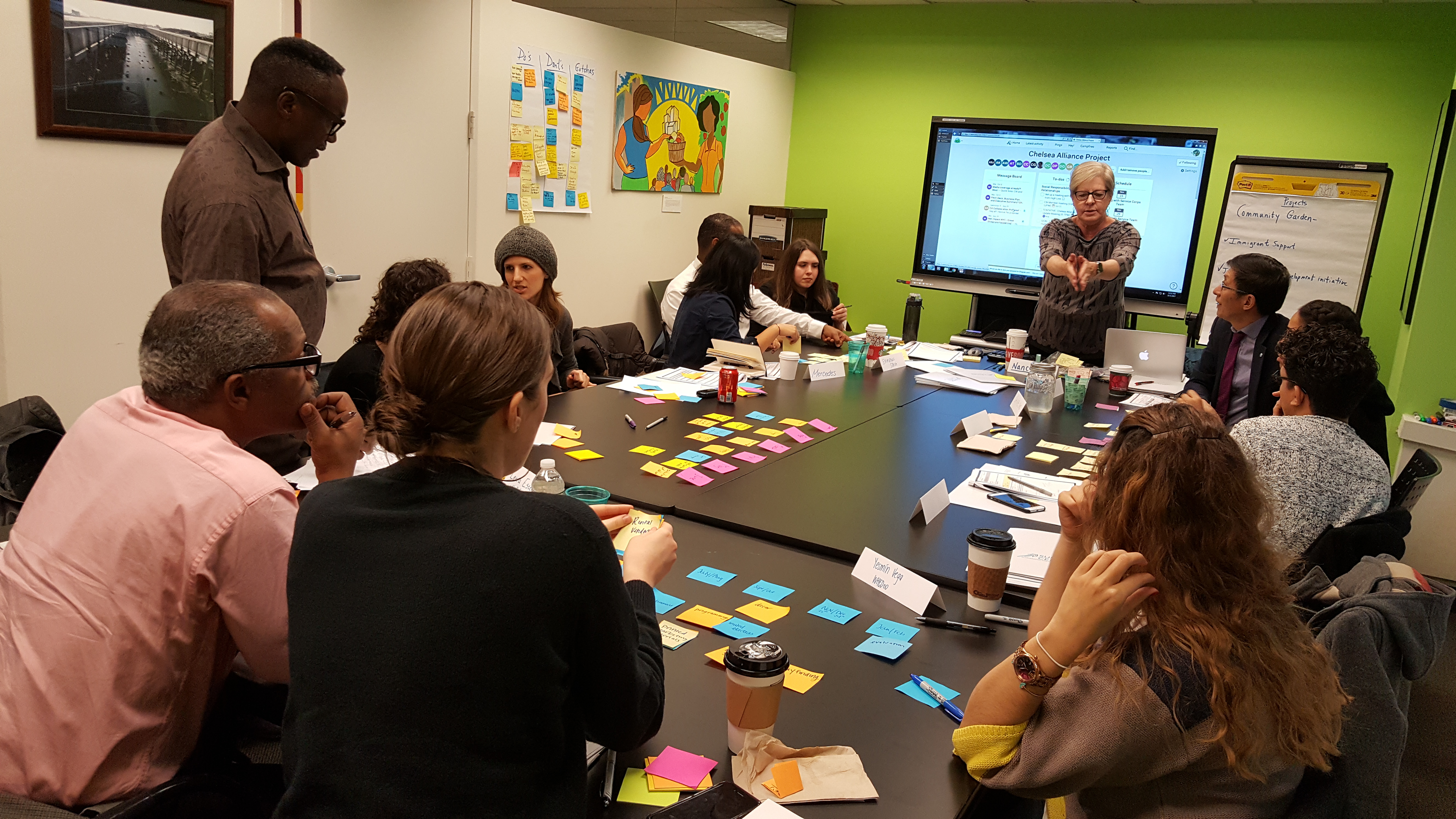 workshop with multiple attendees sitting at a table with multicolored post-it notes placed on the surface