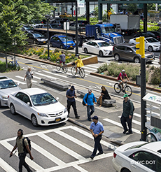 Aerial shot of a busy intersection shows pedestrians, cyclists and vehicular traffic.