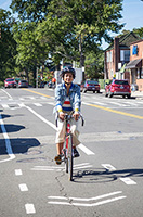 A cyclist rides on a bike lane on a street.