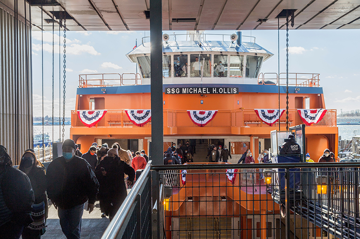 Passengers disembark from the SSG Michael H. Ollis ferry, which is decorated with patriotic flags.