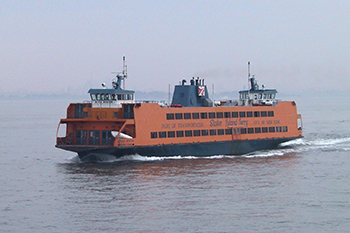 An orange ferry travels in the New York Harbor, named for Alice Austen.