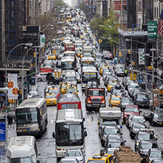 Cars, buses, trucks, and taxis on a congested Midtown Manhattan street.