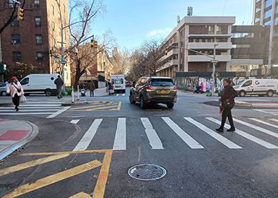 A car turns left around a painted yellow area with flexible posts, helping the driving to slow down and turn wide.